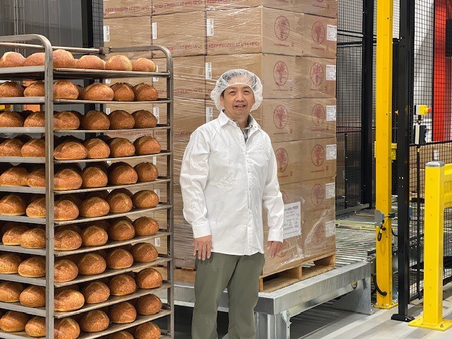 Dinh Nguy stands in front of sourdough bread and boxes in his West Sacramento bakery.