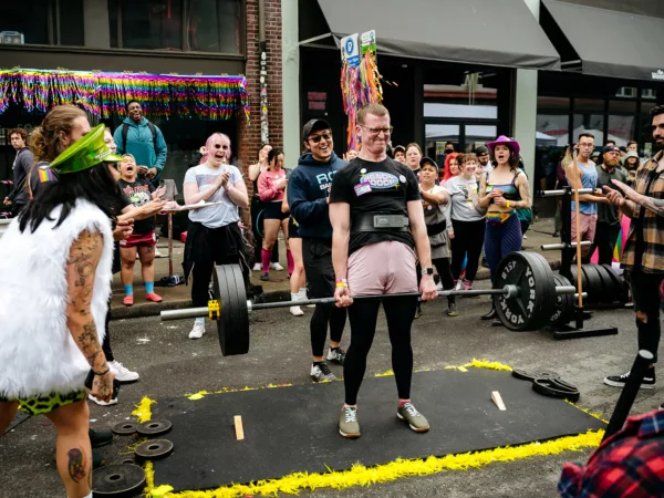 People cheer on a participant in a powerlifting competition in the street in Seattle