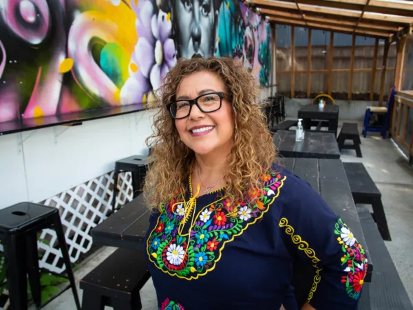 Lucy de Leon stands in the patio at Salsas Locas smiling