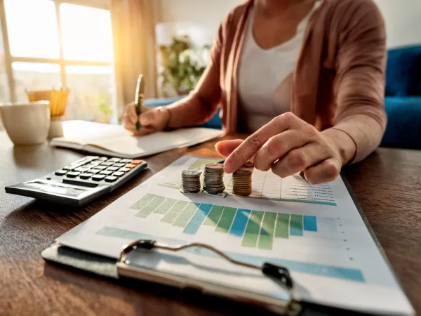 Woman at desk with paperwork calculator and coins