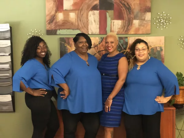 Four people wearing blue outfits pose for the Providence Place Staff Photo