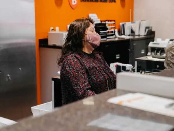 Beneficial State Bank staff member stands at the teller line at our MLK Branch in Portland, OR, smiling behind her mask.