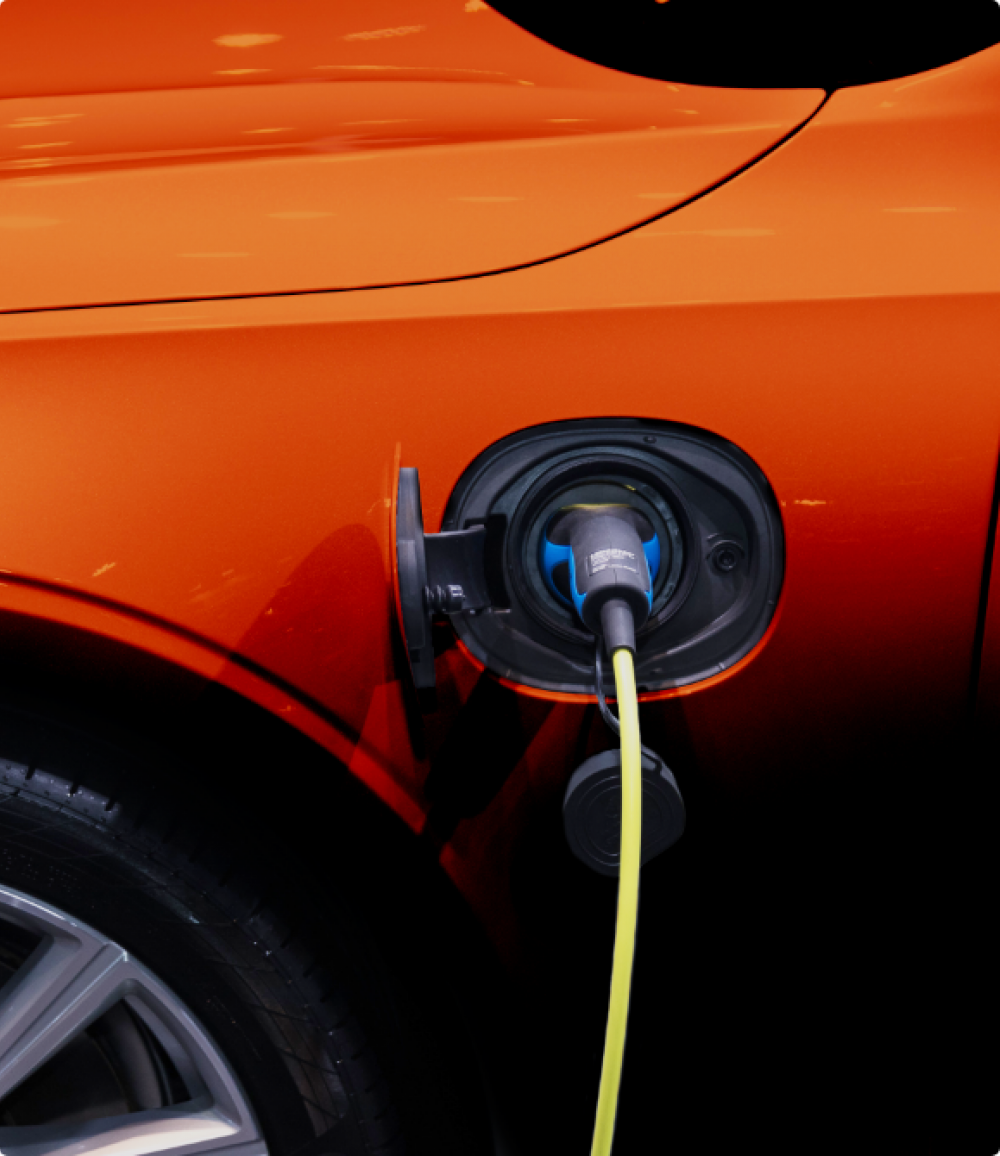 An orange electric car plugged in for charging