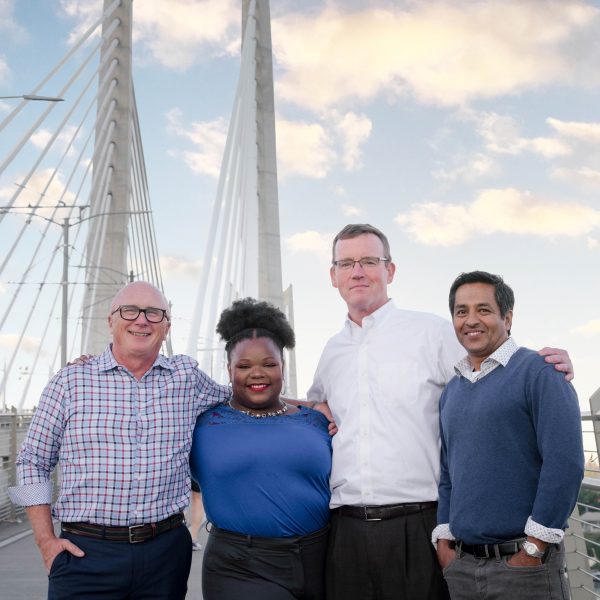 Four Bridge City Law Firm partners standing on a bridge